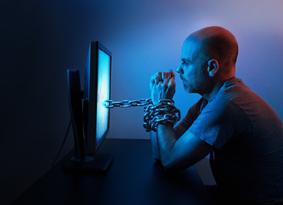 "A man is chained to computer late at night."